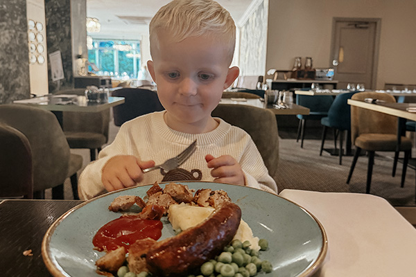 Young boy enjoying sausage, mash and peas in the Gold Room at Hotel Collingwood